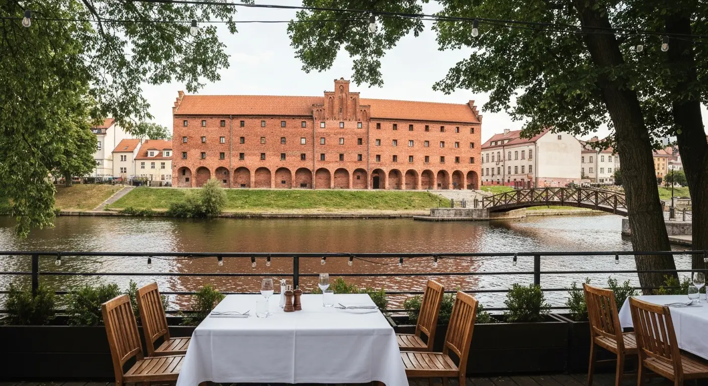 Nakryty stolik na tarasie restauracji nad Mlynowka przy Wyspie Mlynskiej w Bydgoszczy, w tle zabytkowe spichrze i rzeka.