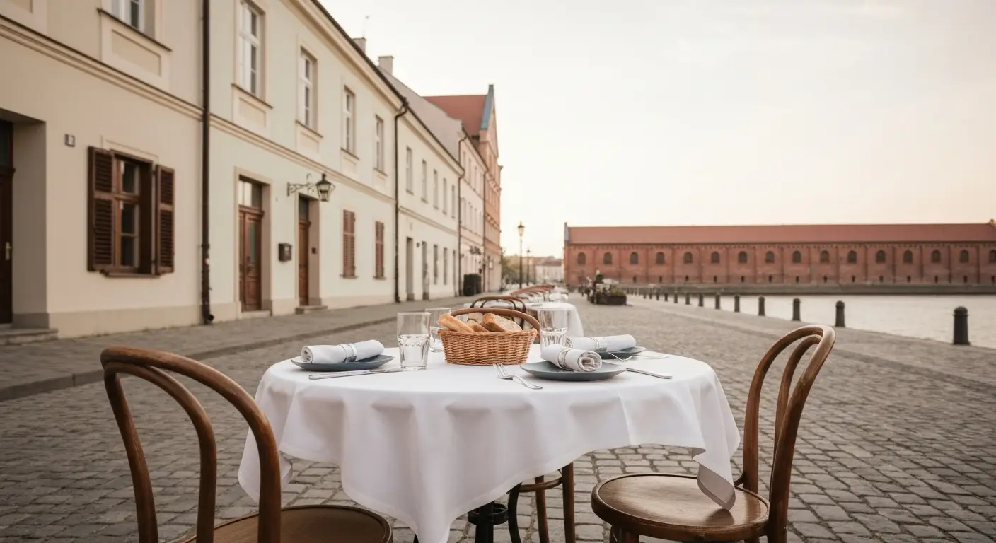Stolik restauracyjny z zastawa na brukowanej uliczce bydgoskiej starowki, w tle kamienice i ceglane spichrze nad Brda